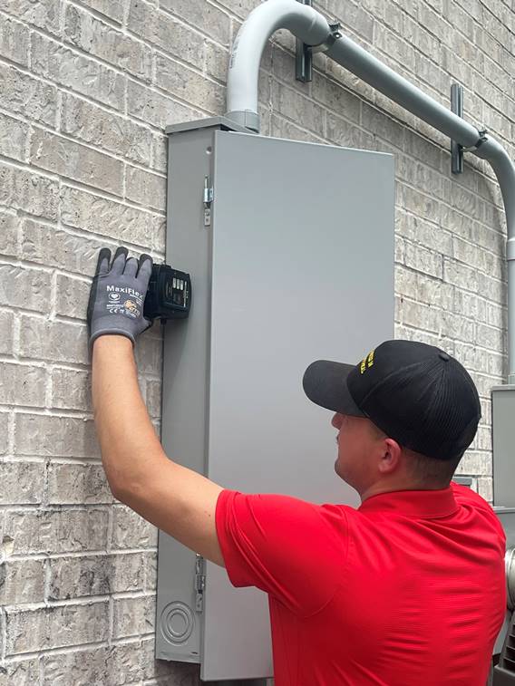 Pluggedin Electrical- A man is repairing an electrical panel mounted on a wall