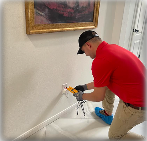 Plugged In Electrical- A man in a red shirt and black hat is fixing switch